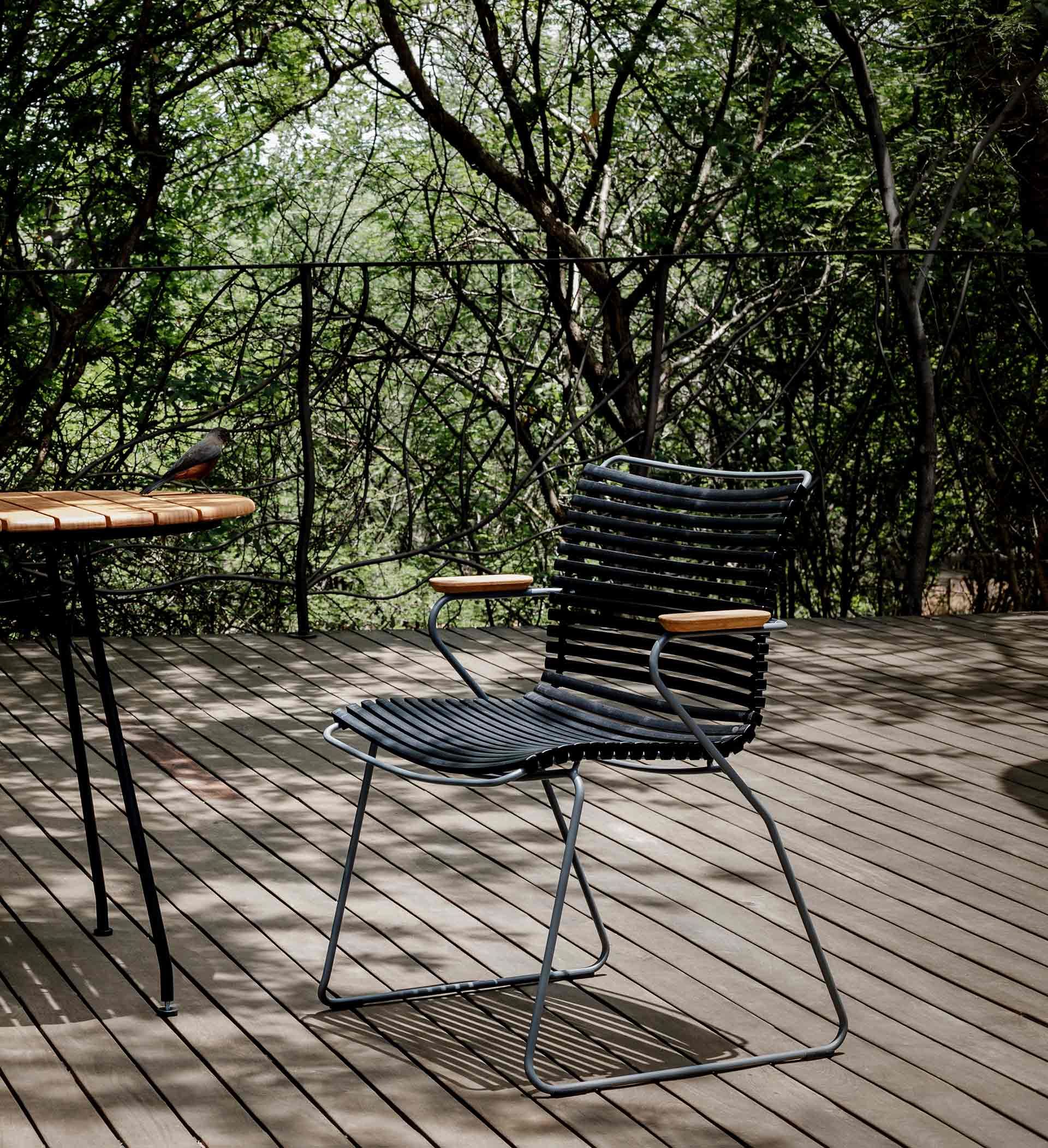 Der Houe Click Dining Armlehnstuhl mit niedriger Lehne auf einer sonnigen Terrasse.