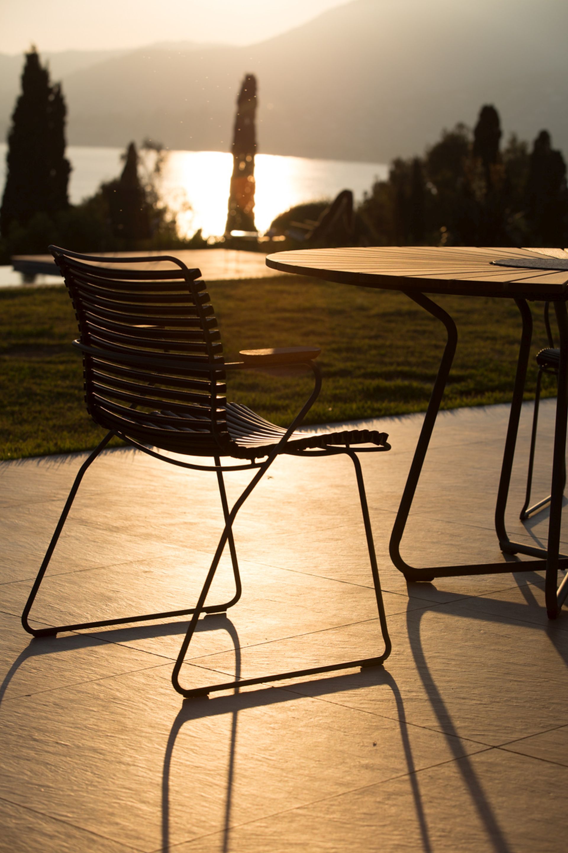 Der Houe Click Dining Armlehnstuhl mit niedriger Lehne bei Sonnenuntergang.