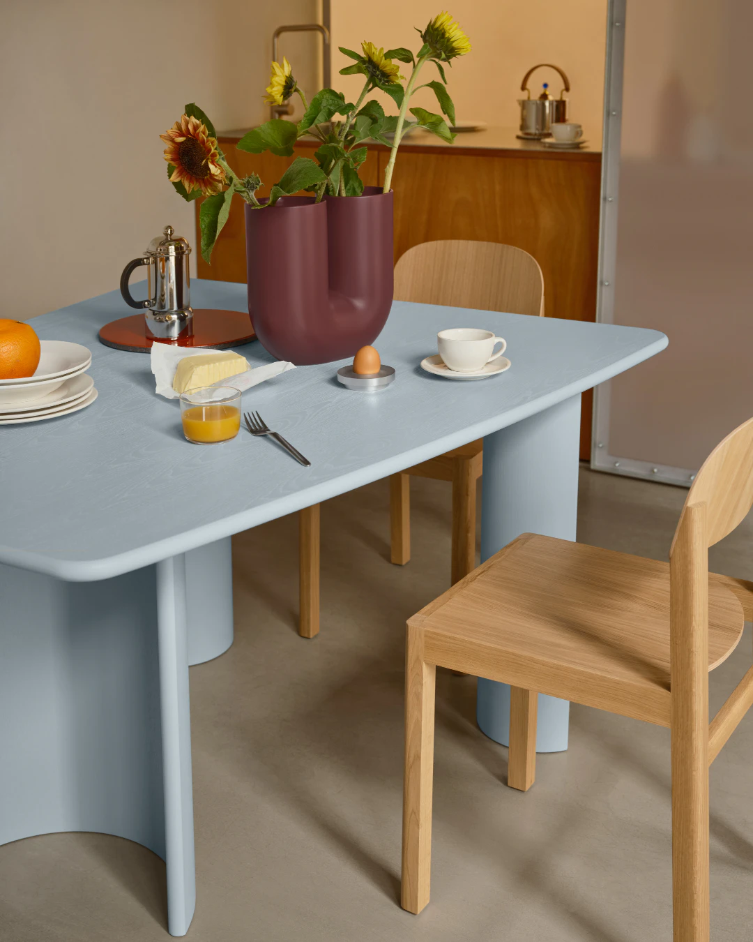 Ein hellblauer Tisch und holzfarbene Stühle